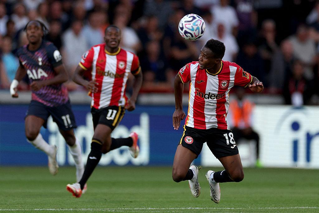 A Brentford player heads the ball as Tottenham players track the play