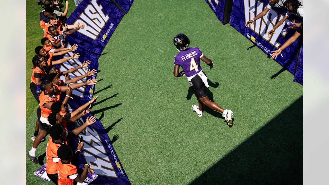 Zay Flowers runs onto the Ravens training camp practice field between rows of fans