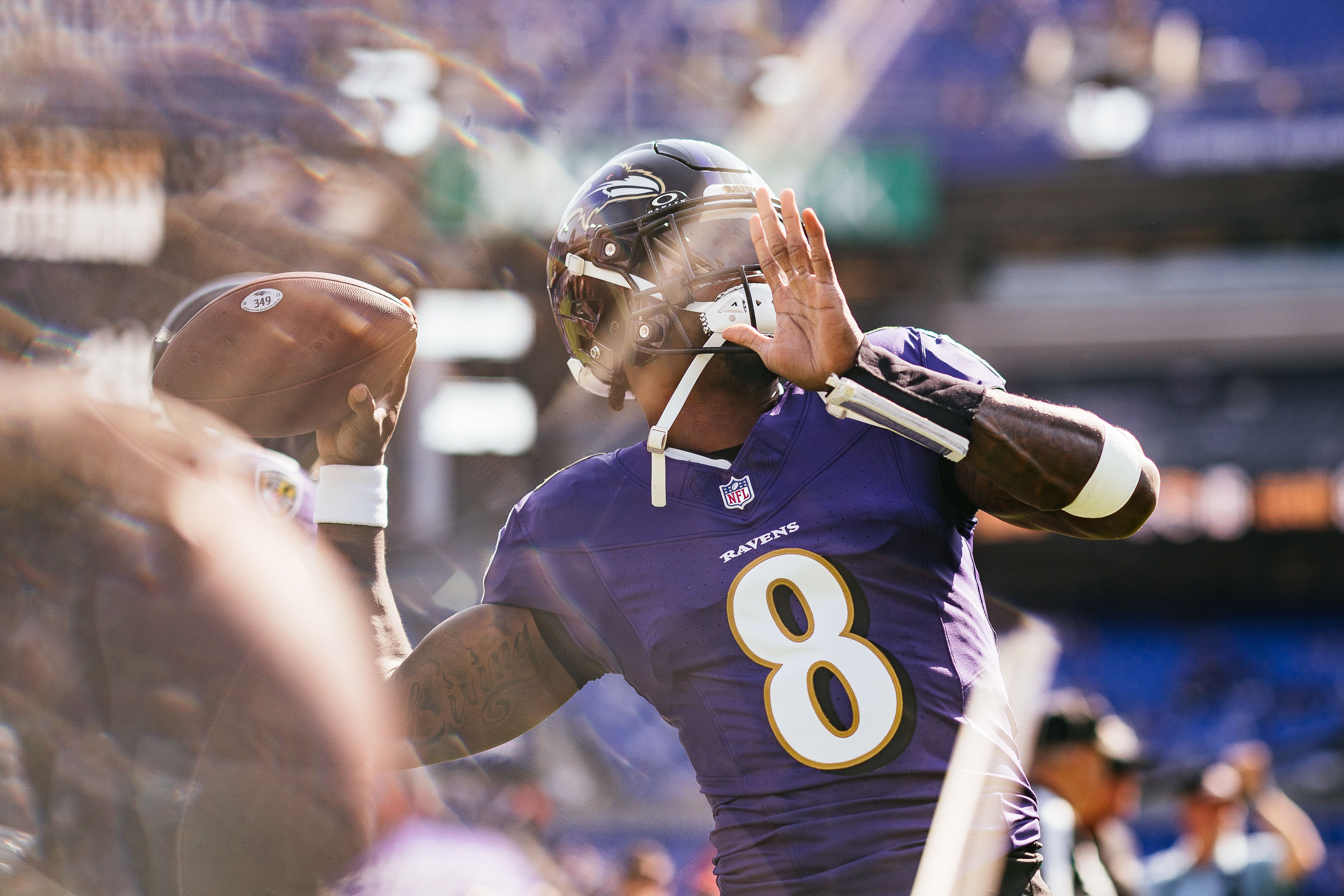 Lamar Jackson throws a football while warming up in a purple Baltimore Ravens uniform
