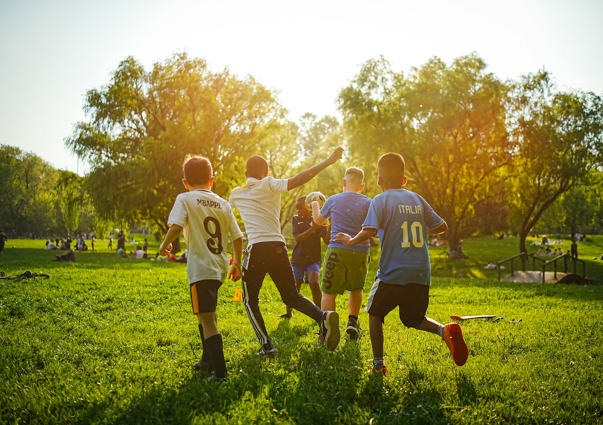 Children playing an informal game of soccer in a sunny public park