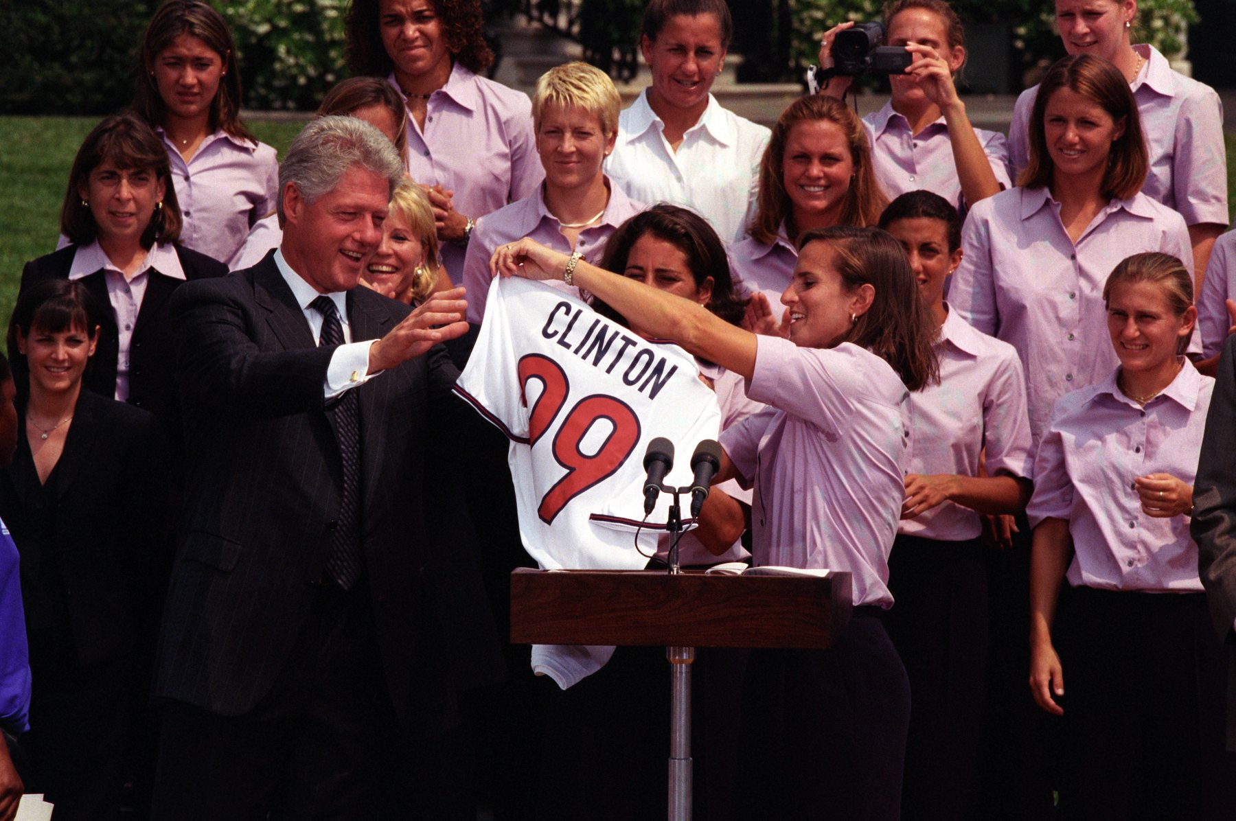 The 1999 World Cup-winning USWNT presents President Bill Clinton with a jersey at the White House